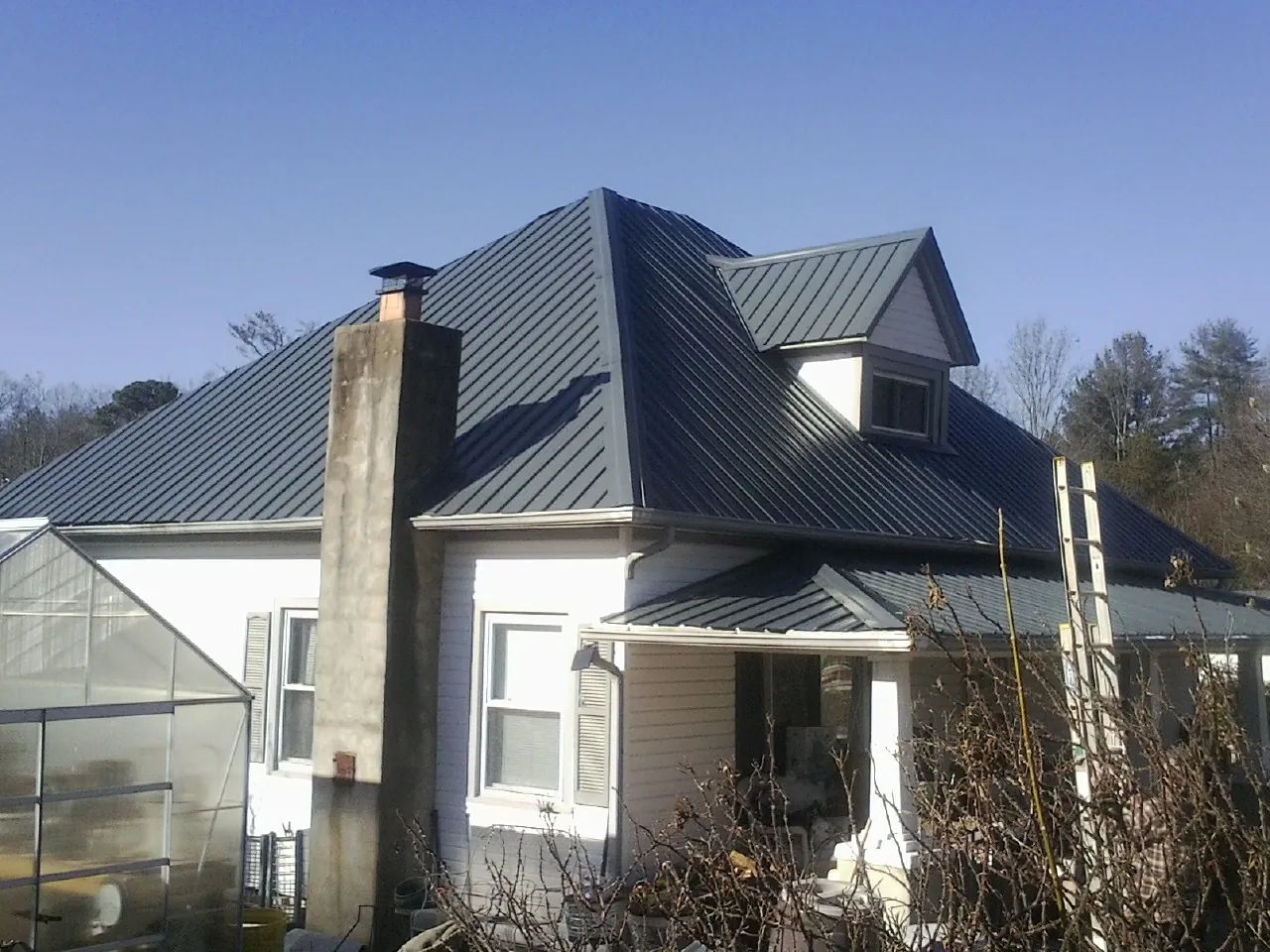 Dark blue standing seam metal roof on a white farmhouse with dormer — Slate & Tile Roof Repair by Roofing Brothers in Spruce Pine
