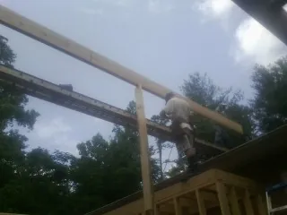 Carpenter setting a ridge beam over a new addition frame — Ice Dam Removal by Roofing Brothers in Spruce Pine