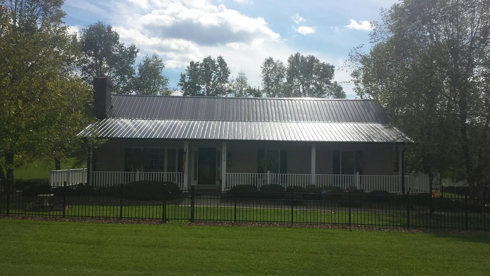 Gray metal roof on a brick ranch with a full width front porch — Gutter Guard Installation work by our crew in Spruce Pine