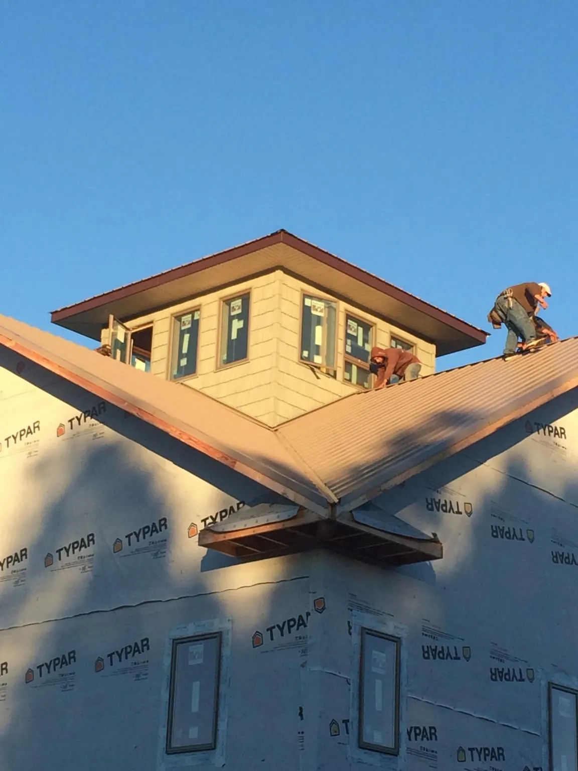 Roofers working around a rooftop cupola on a new metal roof at sunset — Roof Waterproofing in Spruce Pine by Roofing Brothers